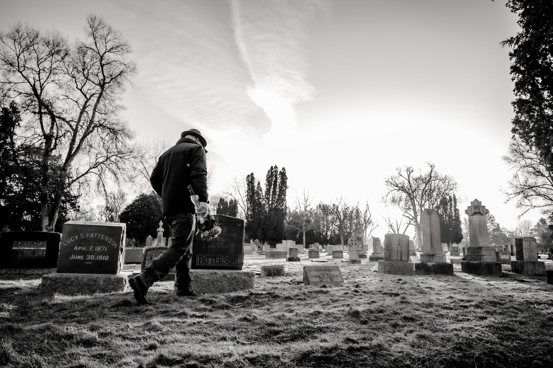 monochrome photo of man walking in cemetery